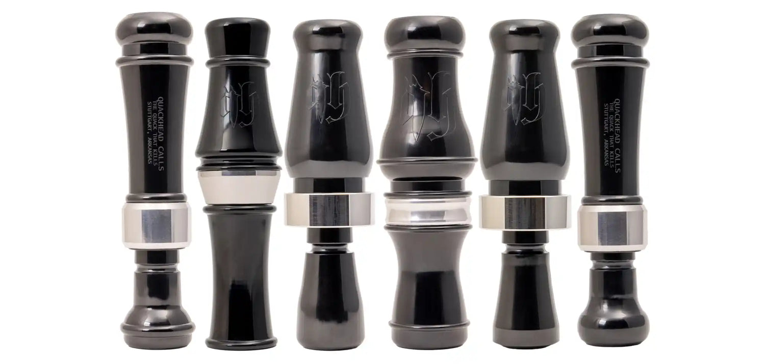 A set of six black and silver duck calls.