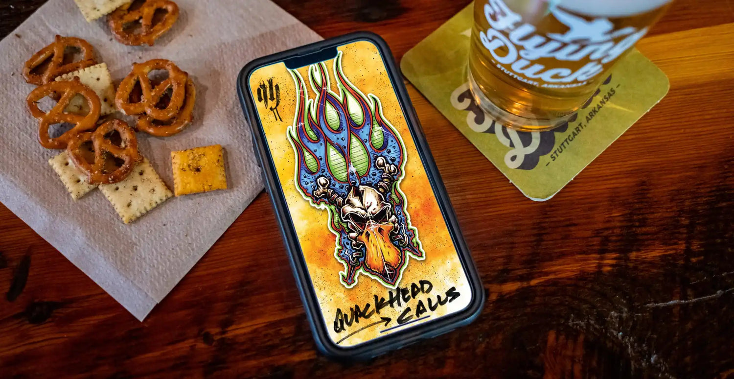 A smartphone displaying a colorful, fiery skull graphic, alongside pretzels, crackers, and a glass of beer.