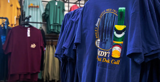 A blue t-shirt with a colorful duck call graphic.