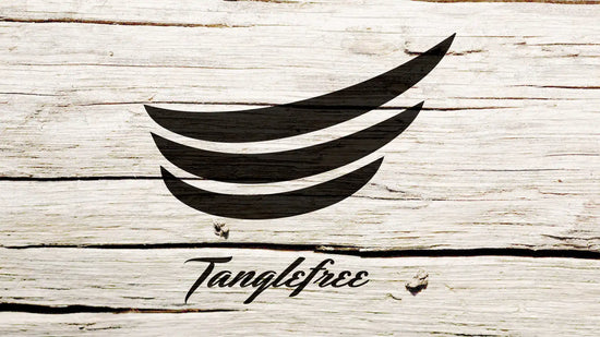 A stylized black logo resembling curved lines or wings, with the word ’Tanglefree’ in script font below it, against a white wood grain background.