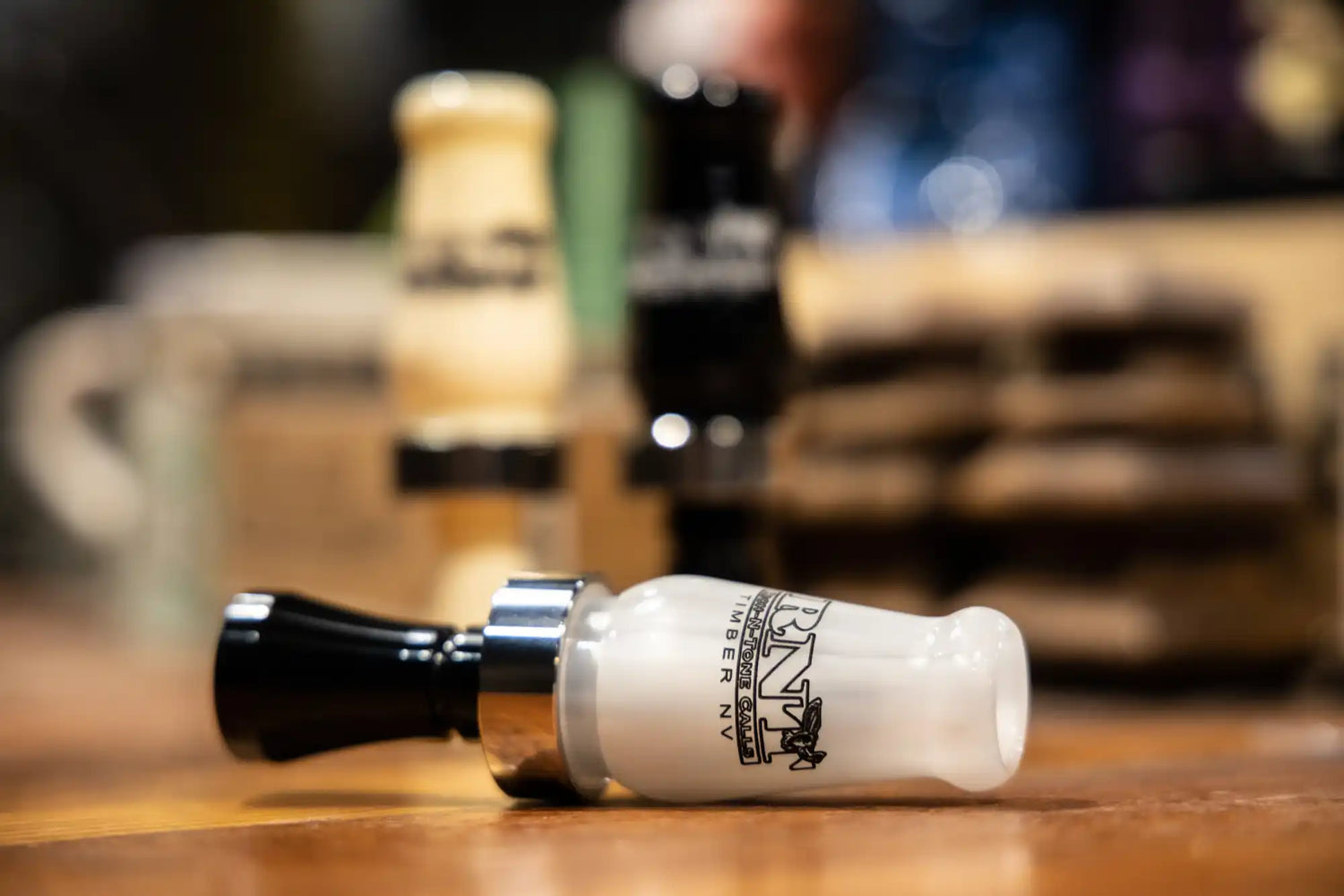A white and black duck call with a silver band.